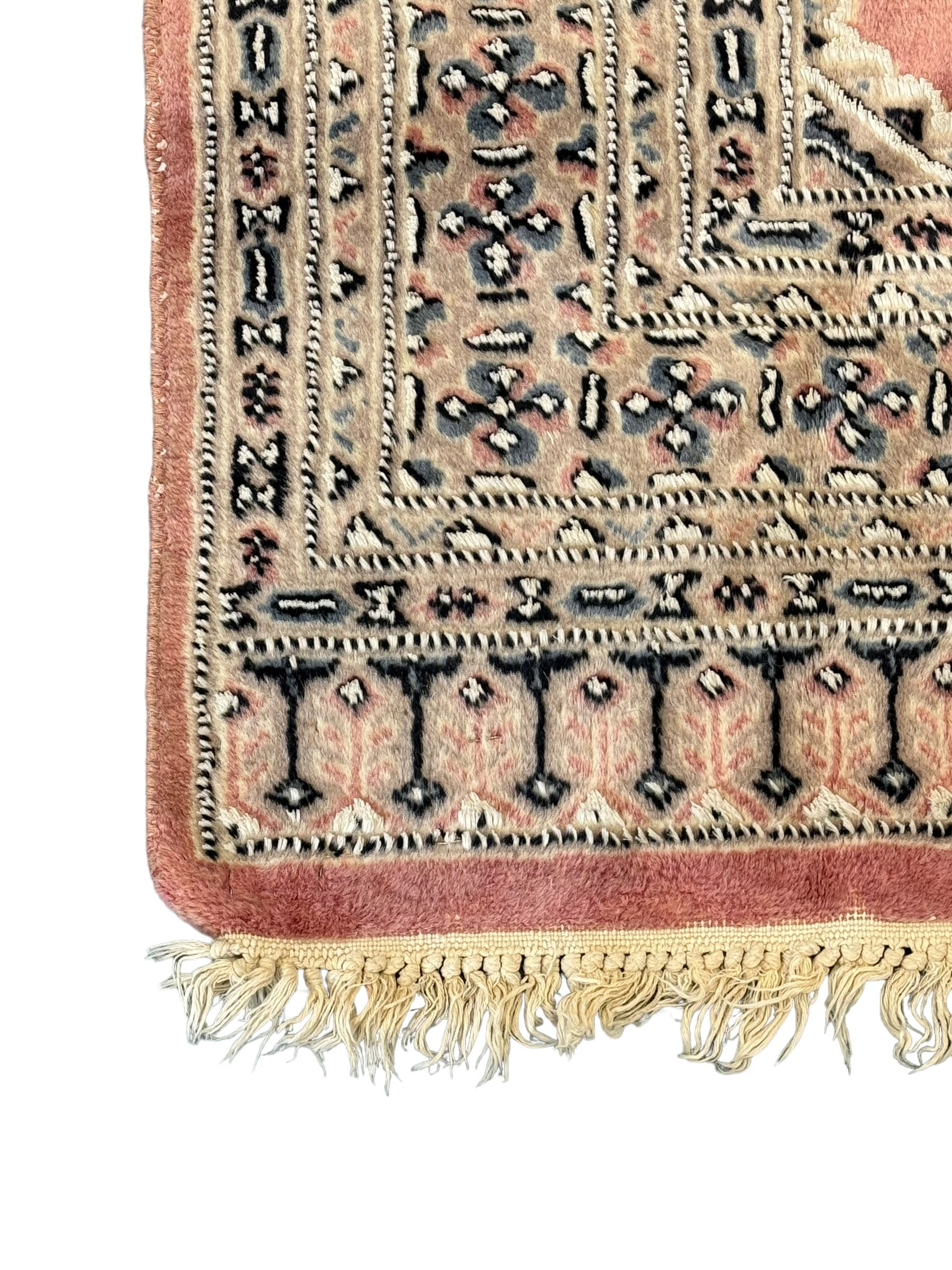 Persian design pale pink ground rug, the field divided into panels and decorated with Gul motifs, wide multi-band border with geometric patterns 