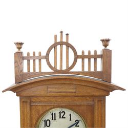German-Art Deco 8-day longcase clock in an oak case, with a curved top and open fence work pediment, with reeded decoration and a fully glazed case door with a rectangular brass open work panel, on a tall rectangular plinth with a period  carved motif, circular slivered dial with Arabic numerals and spade hands, two train HAC (Hamburg and American Clock Company) weight driven movement, sounding the hours and half-hours on a coiled gong, with weights and pendulum.   