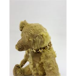 Early 20th century English teddy bear, with wood wool filled body with jointed limbs, felt covered paw pads, five claw stitching to feet and elongated arms with spoon shaped paws H14