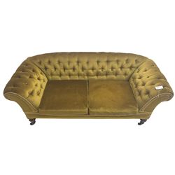 Victorian walnut framed two seat sofa, upholstered in buttoned  olive green fabric with sprung seat and scrolled arms, raised on turned supports with ceramic castors