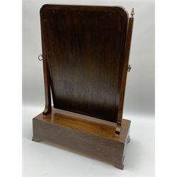 Georgian mahogany swing toilet mirror, the rectangular plate with gilt slip and moulded frame, supported on tapering horns with brass finials, upon a base with shaped front fitted with three drawers, and ogee bracket feet, H54cm W38cm D21cm