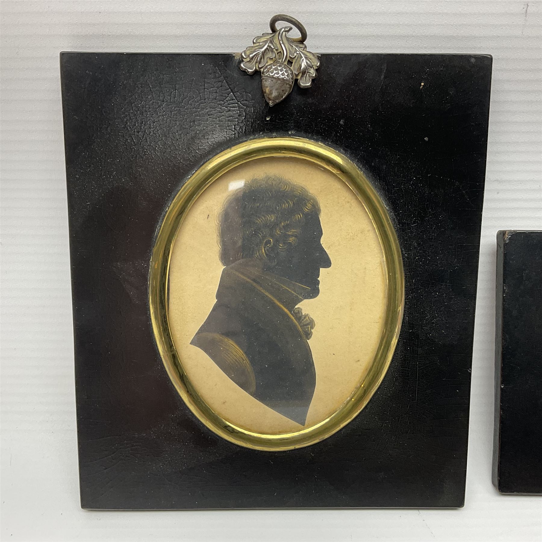 Two 19th century silhouettes, the first example depicting the side profile of Thomas Smallwood, with details highlighted in gilt and label verso, the second example depicting the side profile of an older gentleman, both in lacquered wooden frames, together with a enamel portrait of a young female, tallest frame H16.7cm