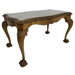 Mid-20th century figured walnut serpentine coffee table, inset glass top and foliate carved edge, raised on cabriole supports with acanthus moulded knees and ball and claw feet