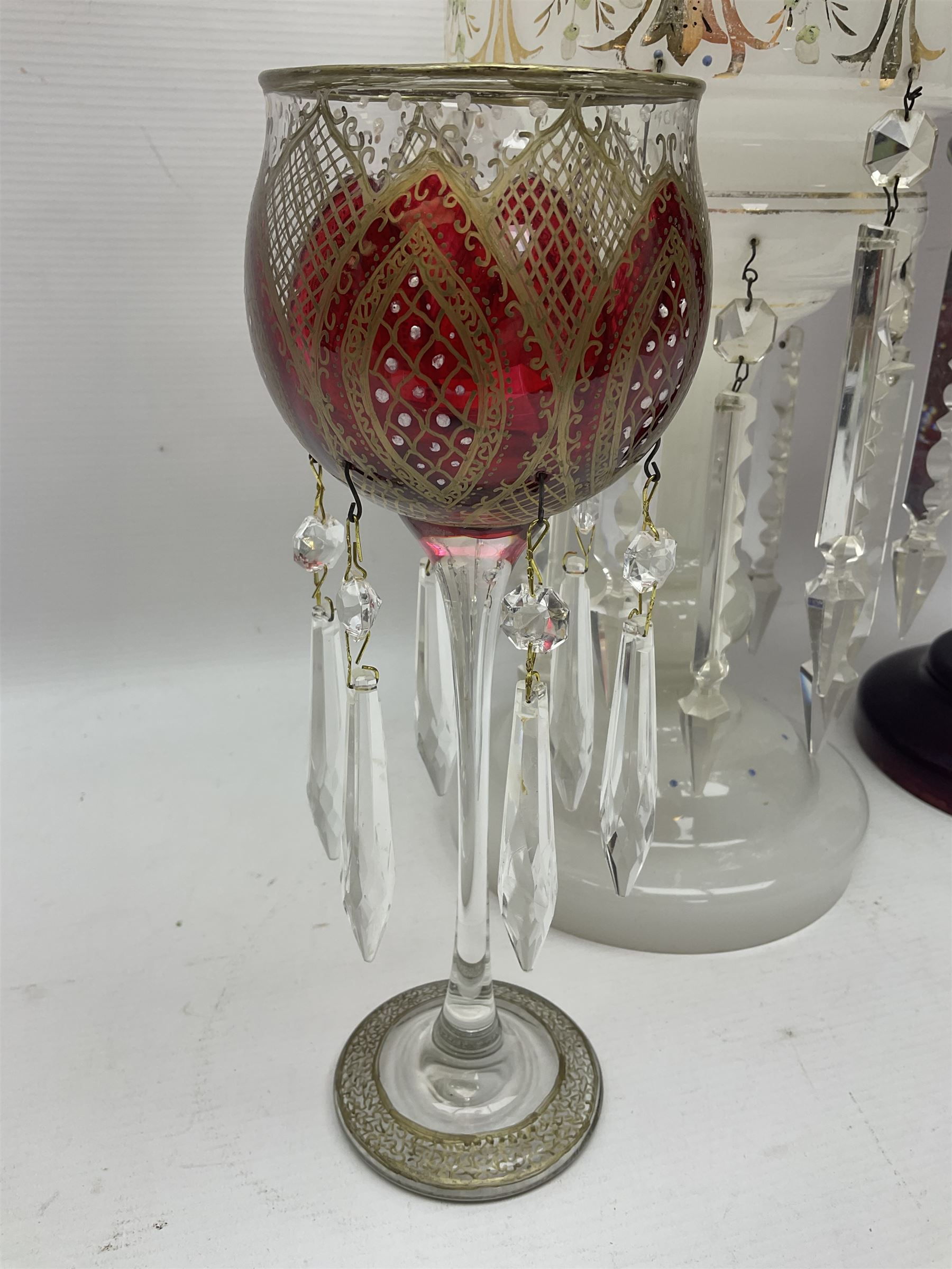 Bohemian red glass lustre, painted with stylised floral and foliate decoration, together with a milk glass example and two bohemian goblets converted to lustres 