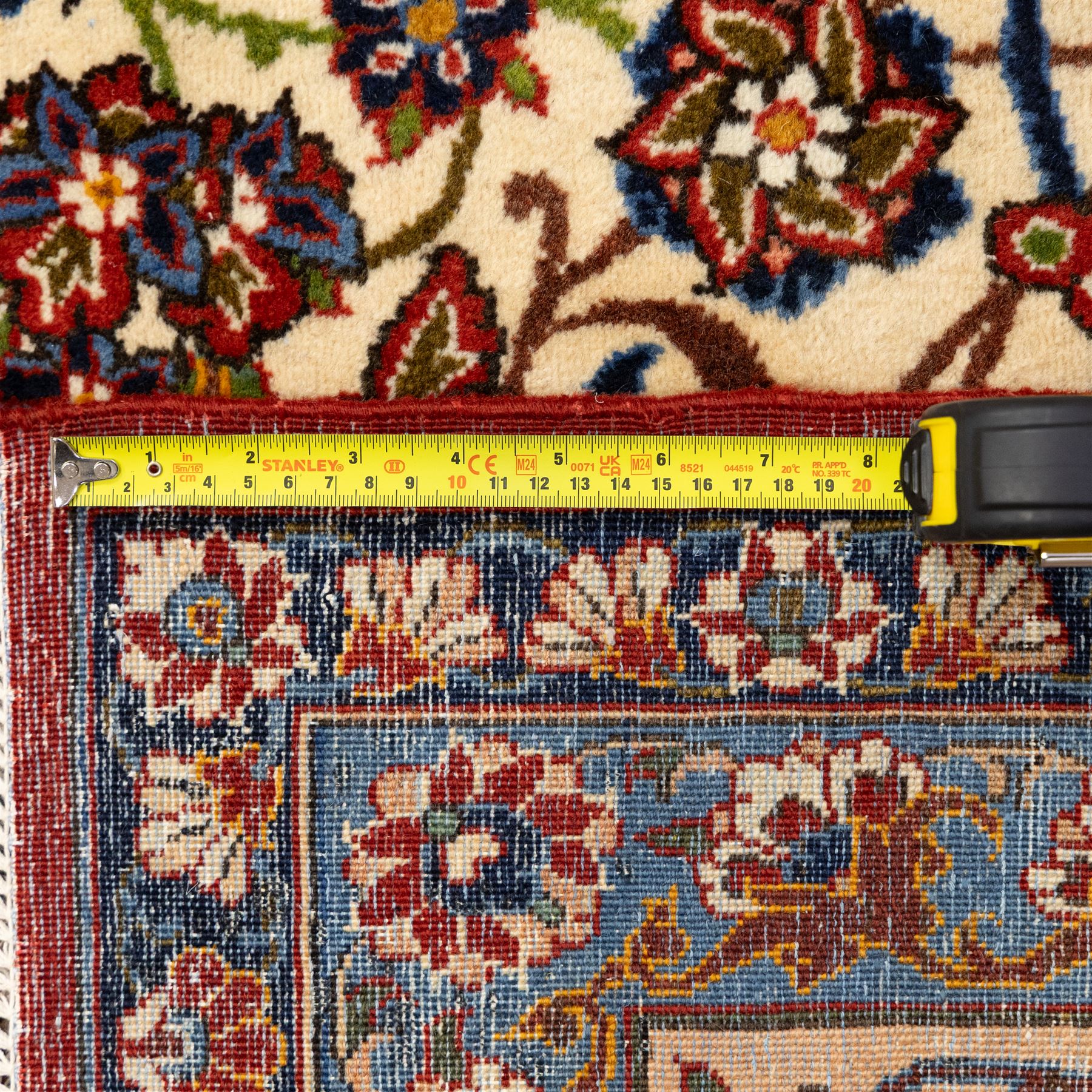 Central Persian Najafabad hand-knotted carpet, ivory field with an all-over scrolling floral design of palmettes, rosettes, and leafy vine work, enclosed by a wide floral main border flanked by multiple guard borders in madder red, indigo blue, green, and pale ochre, with cotton fringe ends 