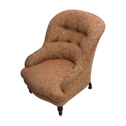 Late Victorian nursing chair, of tub form with deep buttoned backrest, upholstered in pink damask fabric with foliate motifs, raised on turned mahogany legs with brass caps