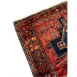 Persian Kurdish rug, red ground field decorated with small stylised motifs with triple linked medallions, three band border, the main band with scrolling design and decorated with floral motifs
