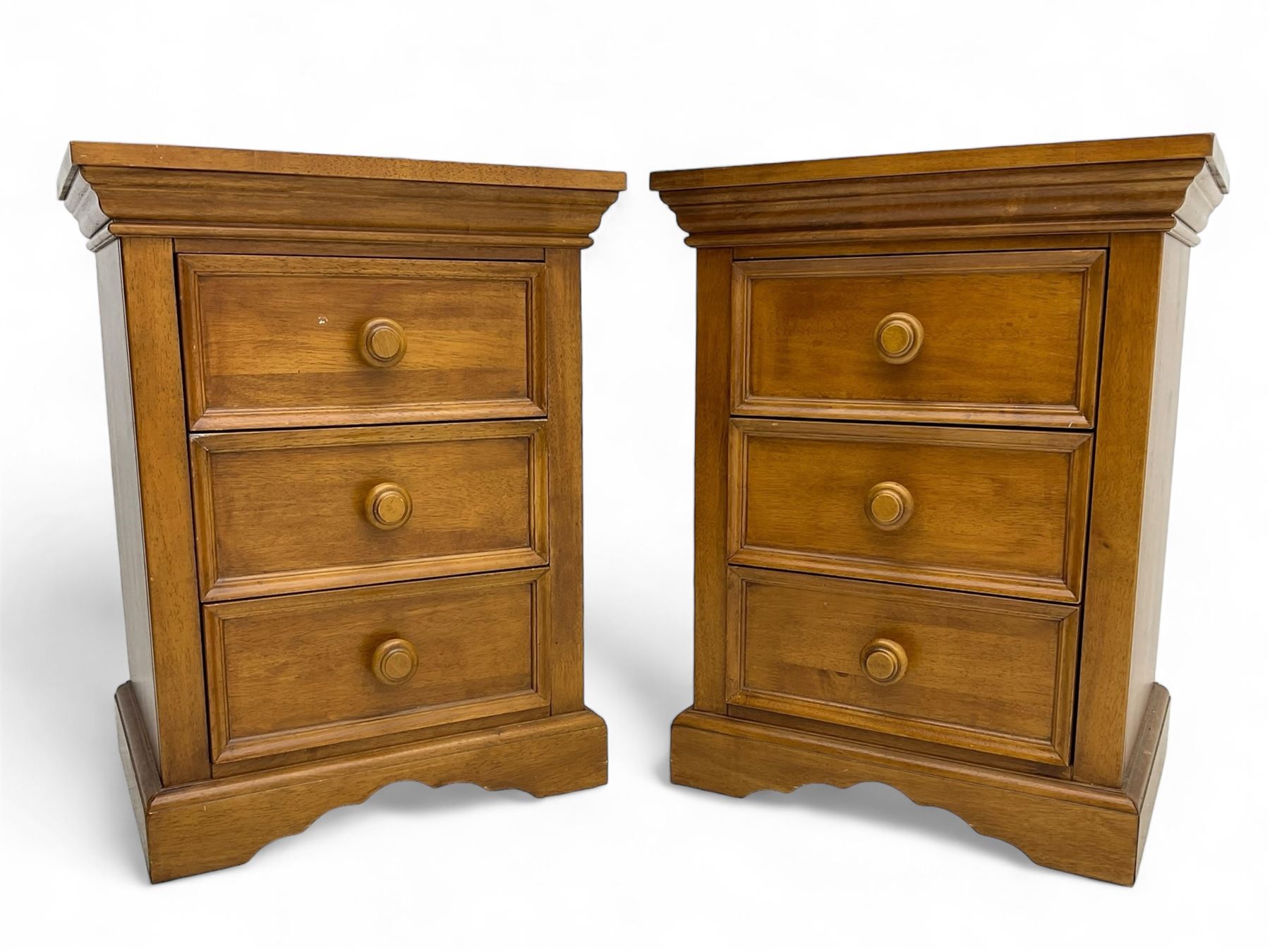 Pair of contemporary cherry wood bedside chests, rectangular top and projecting moulded cornice over three drawers, on plinth base with shaped apron