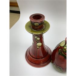 Minton Secessionist vase, with tube-lined stylised flower head decoration upon a red and green ground, printed mark to base 'Minton Ltd, No. 31', together with a matching pair of Minton Secessionist candle sticks, candlestick H17cm