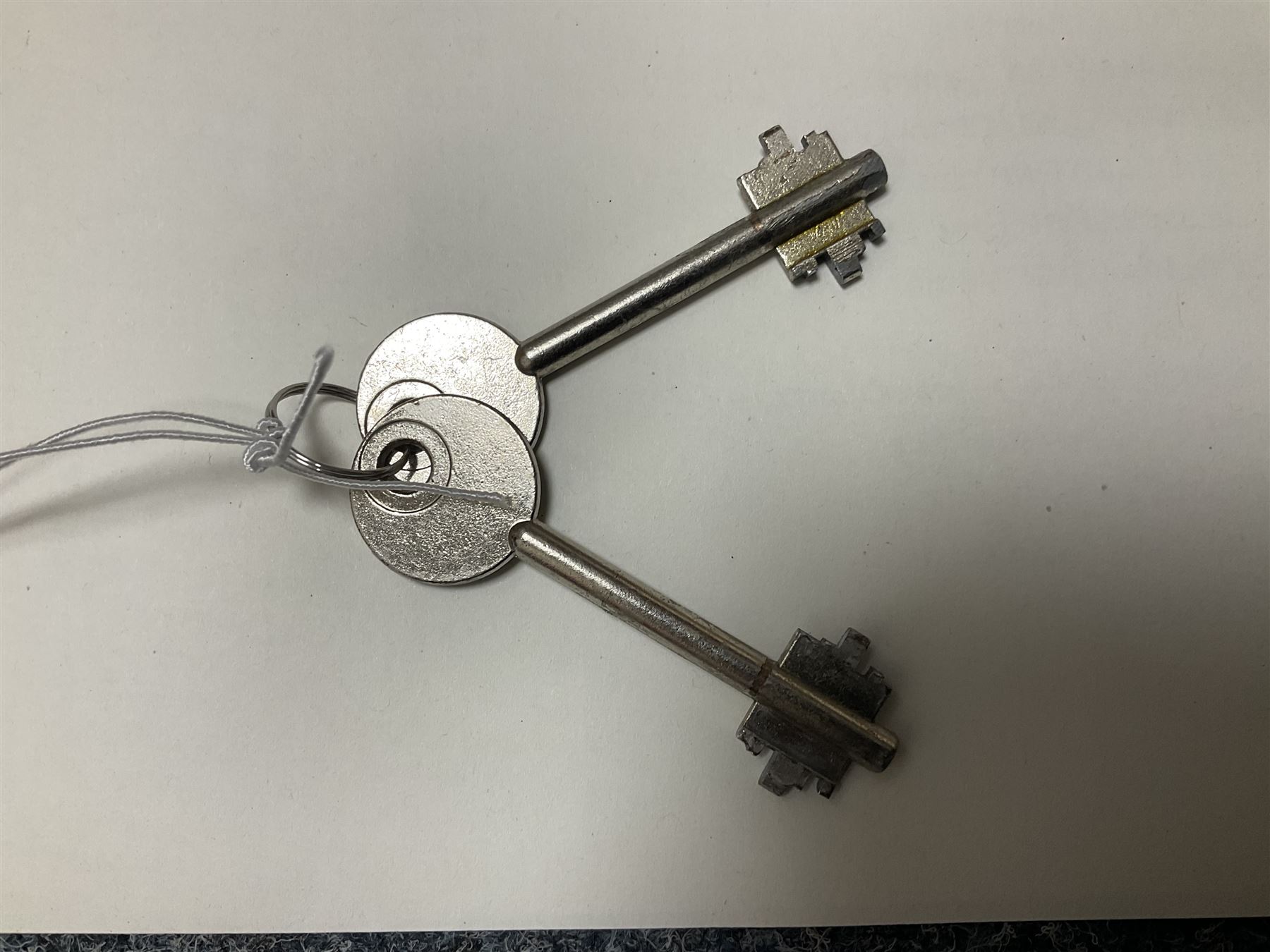 Grey steel wall mounting gun cabinet to accommodate three guns; single door with two locks with two keys for one lock; internally H128.5cm W21cm D17.5cm; externally H129cm W21.5cm D20cm