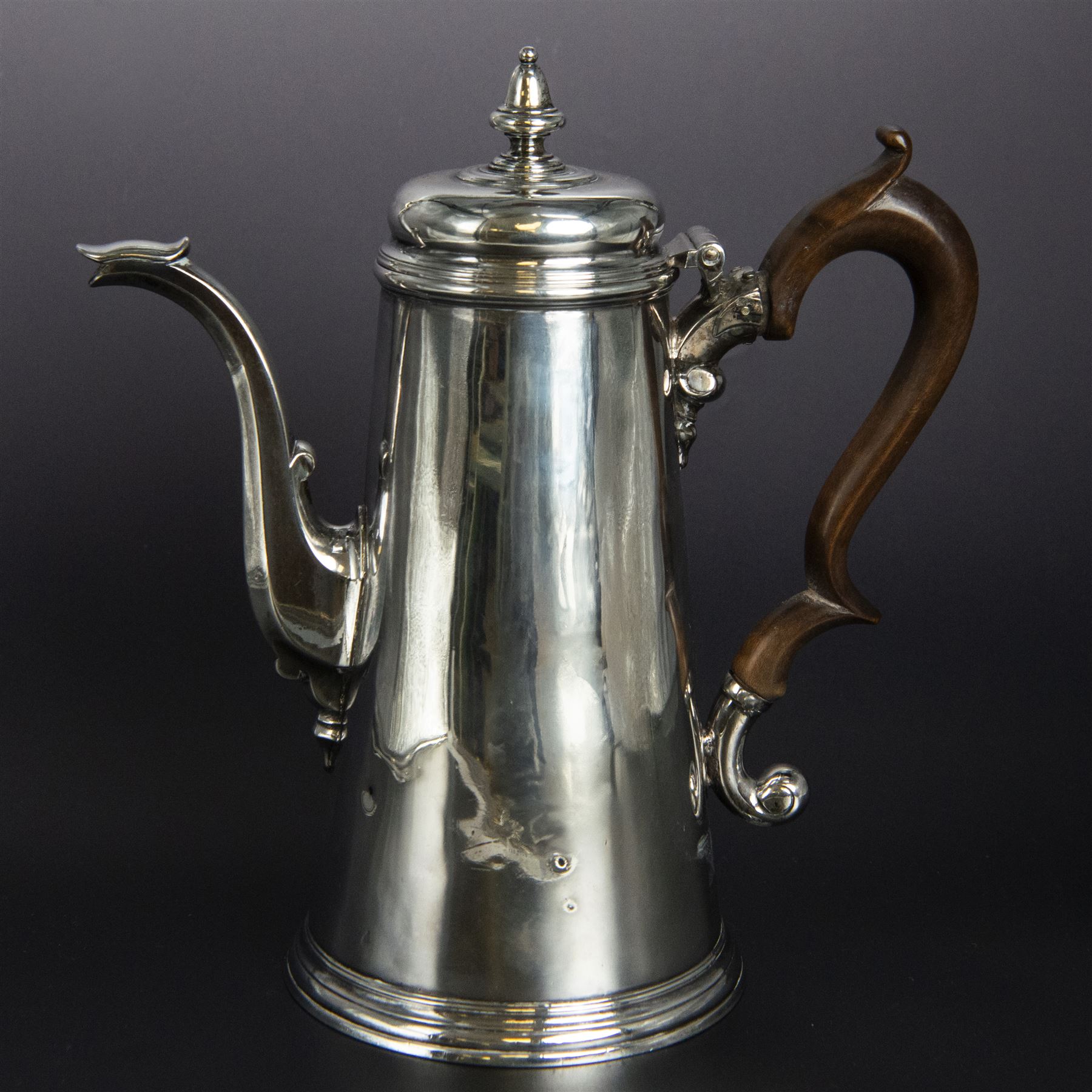 George II provincial silver coffee pot, of tapering cylindrical form, with wooden scroll capped handle, hinged cover with bell finial, and engraved crest to body, hallmarked John Webber of Plymouth, Exeter 1759, H21cm