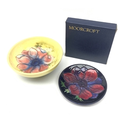 A Moorcroft dish, decorated with the Clematis pattern upon a yellow ground, with paper label beneath, D14cm, together with a Moorcroft pin dish, decorated with the Clematis pattern upon a dark blue ground, with incised marks beneath, D11.5cm, with maker's box. 