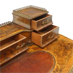 Victorian figured walnut and kingwood-banded ladies writing table, the raised superstructure with three-quarter pierced brass raised gallery back, fitted with five assorted drawers, the serpentine shaped top with oval inset leather surface, the bronze edge of egg and dart form with cartouche corners, fitted with central frieze drawer with inset Sevres-style floral ceramic plaque, raised on cabriole supports with gilt metal mounts