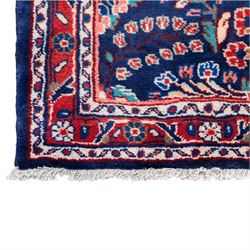 North West Persian runner, the indigo field decorated with repeating symmetrical floral sprays, rosettes and curling foliage in coral, ivory and pale blue tones, enclosed by a red ground trailing flowerhead border and narrow patterned guard bands 