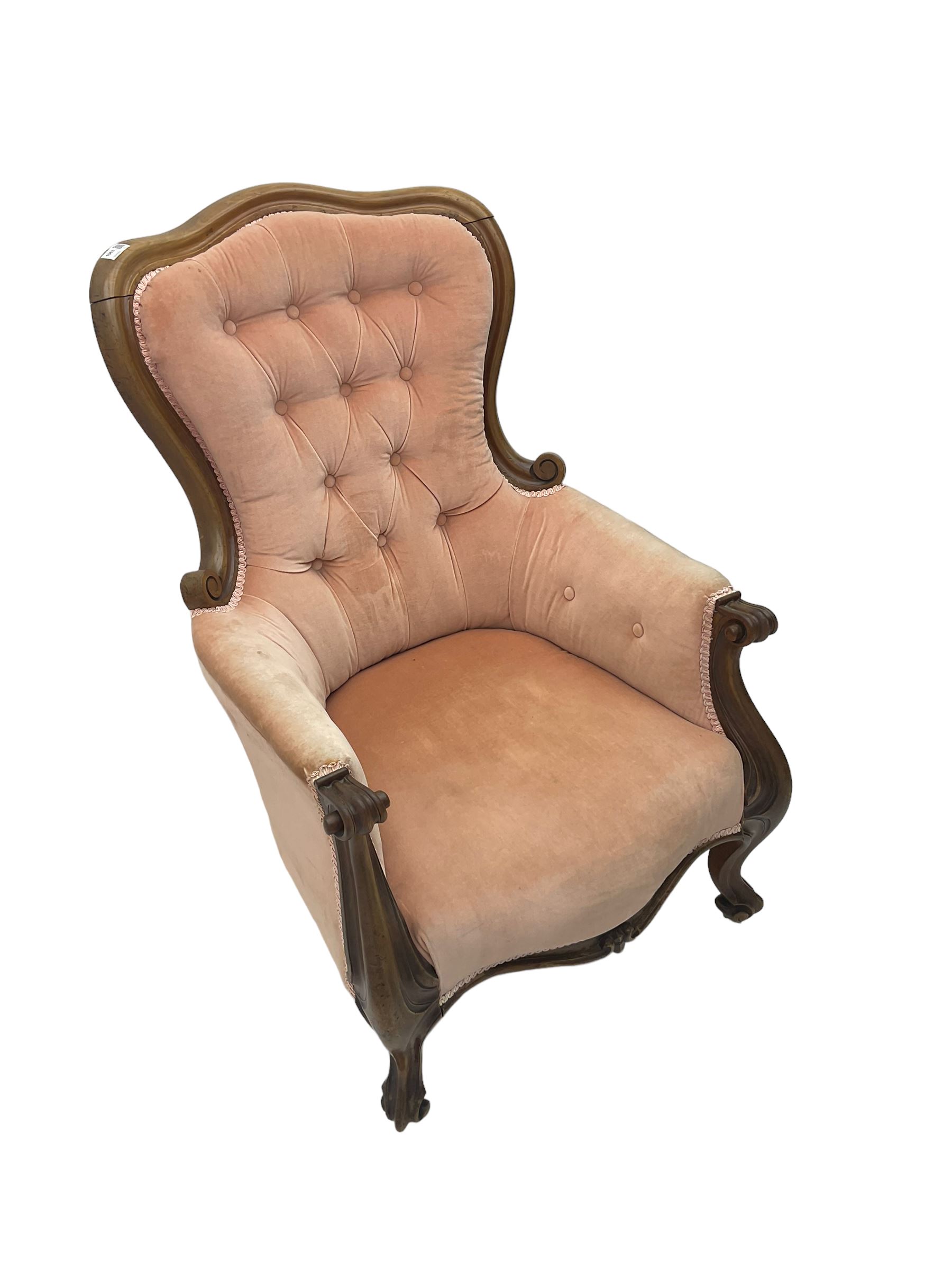 Victorian walnut framed armchair, shaped back with carved and scrolled arm terminals, upholstered in buttoned pale pink fabric, raised on cabriole supports terminating in castors