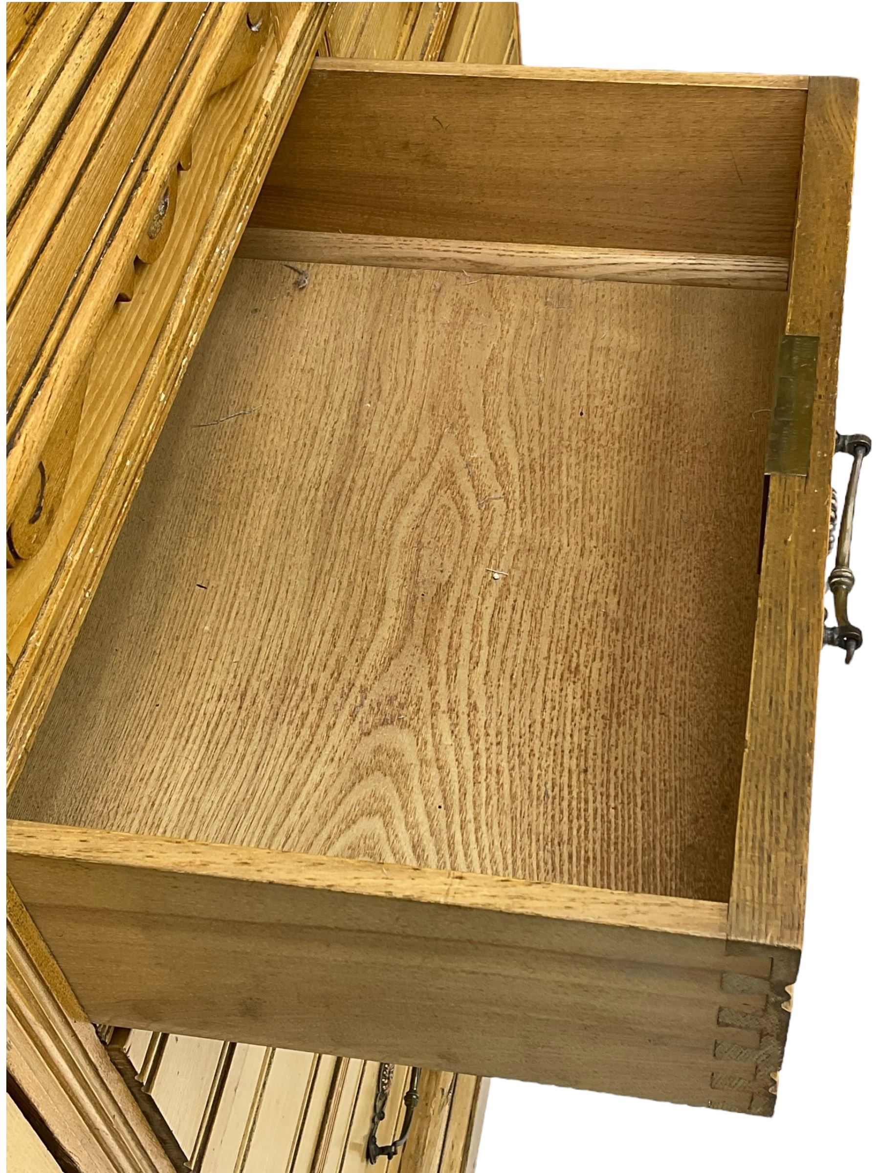 Late 19th century ash combination wardrobe, projecting cornice over foliage carved frieze, the left-hand upright enclosed by mirror glazed door, the right-hand side fitted with double panelled cupboard over two short and three long drawers, the upper panels carved with curled leaves and central scroll cartouche, on bracketed plinth 