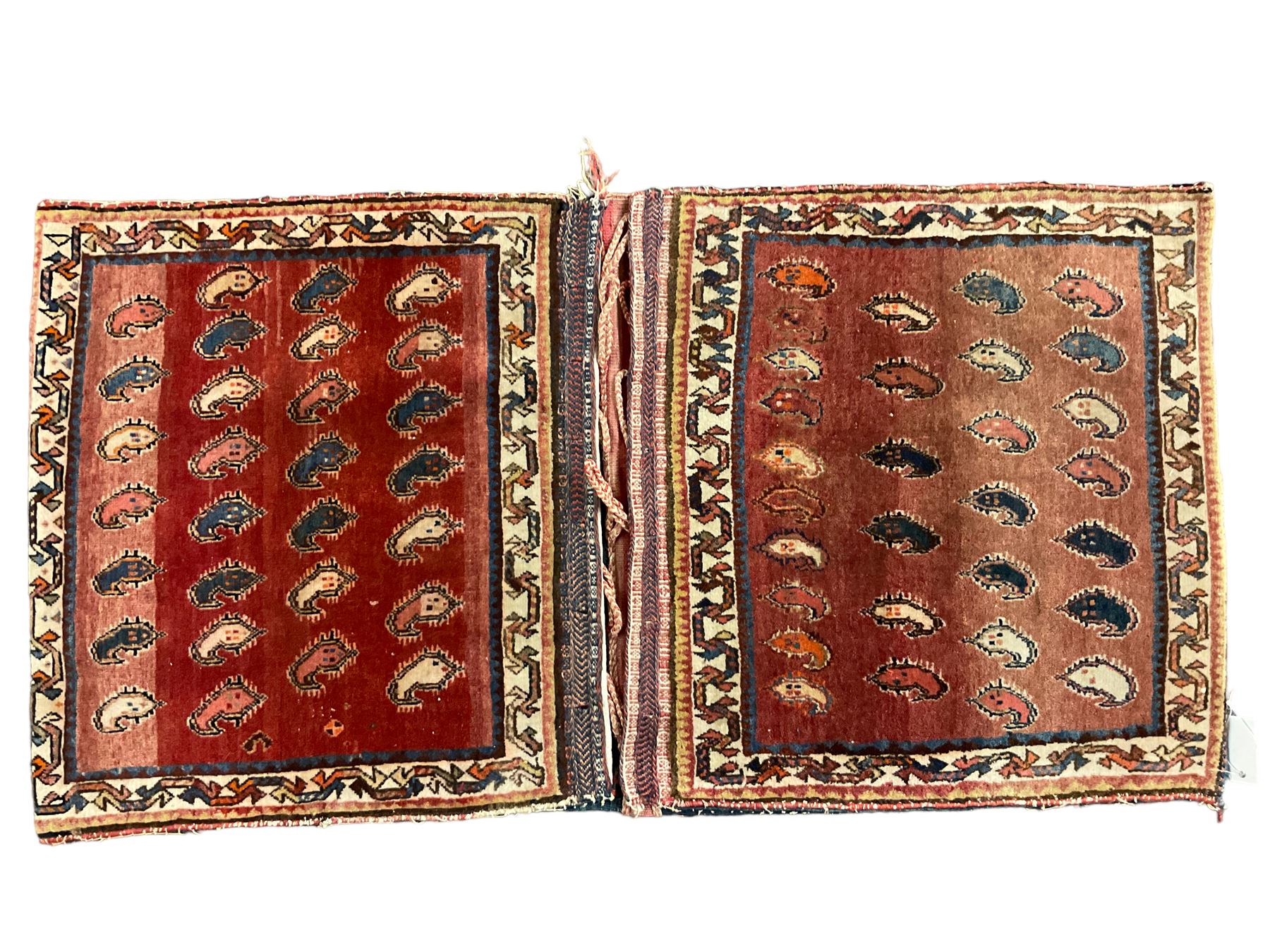 Antique Persian red ground saddle bag, decorated with all-over Boteh motifs, geometric patterned border (127cm x 68cm); Persian indigo ground saddle bag, decorated with two geometric ivory lozenges (113cm x 62cm); Persian red ground saddle bag decorated with lozenges and multi-band border (110cm x 65cm) 