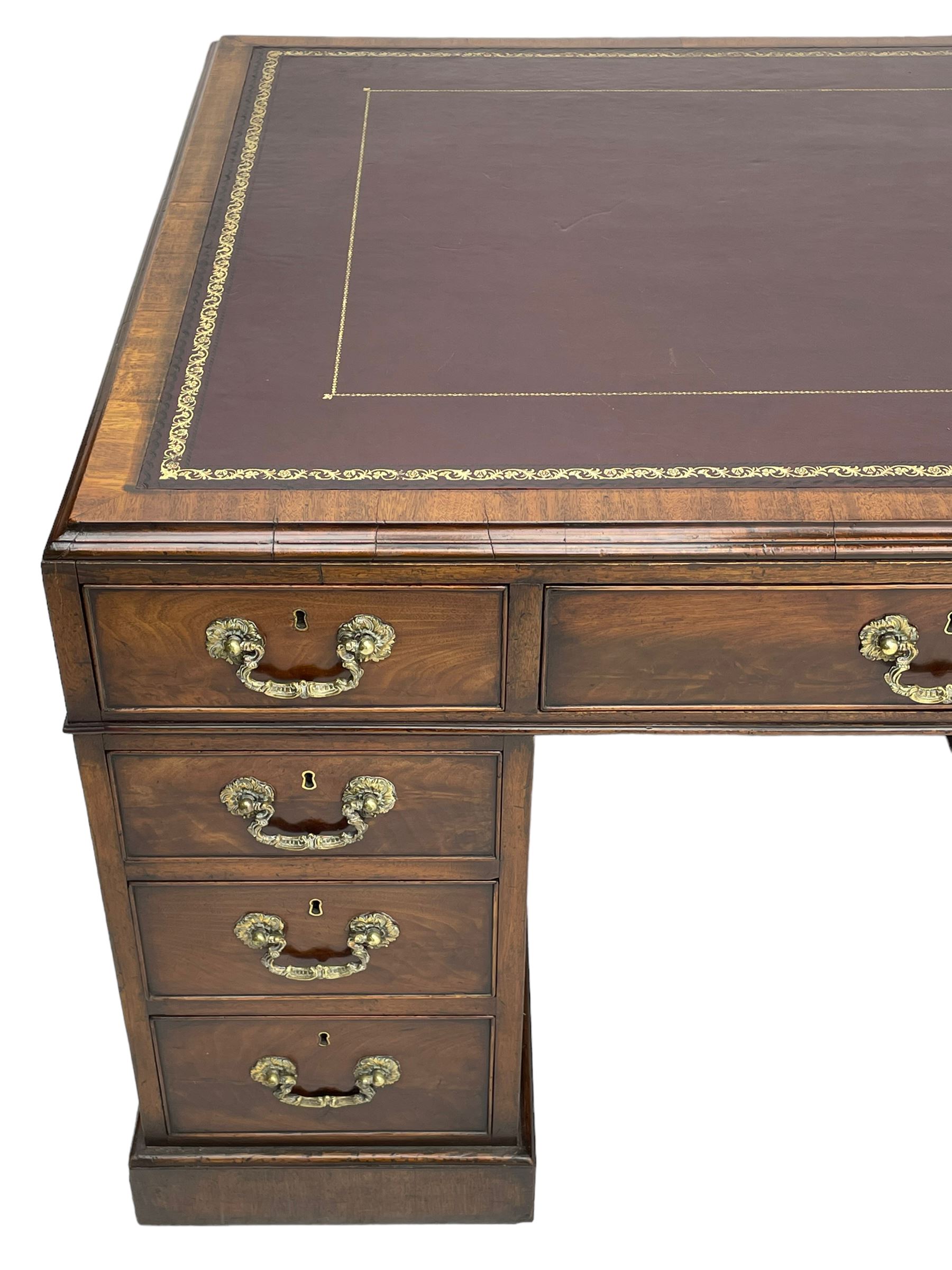 George III mahogany twin pedestal partner's desk, moulded rectangular caddy top with tooled leather inset, one side fitted with nine drawers and the opposing side fitted with single drawer, two false drawers and two panelled cupboards, ornate cast gilt metal handles and handle plates, on plinth base