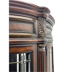  Kevin Charles American walnut demi lune display cabinet with illuminated interior, projecting cornice, two bevel edge glazed doors enclosing two adjustable shelves above single drawer and four cupboard doors with wine rack, carved scrolling supports