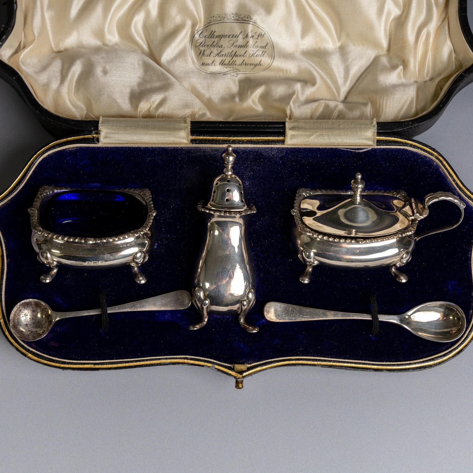1920s silver three piece cruet set, comprising mustard pot and cover, pepper shaker and open salt, together with two matched silver cruet spoons, all hallmarked, contained within fitted tooled leather case