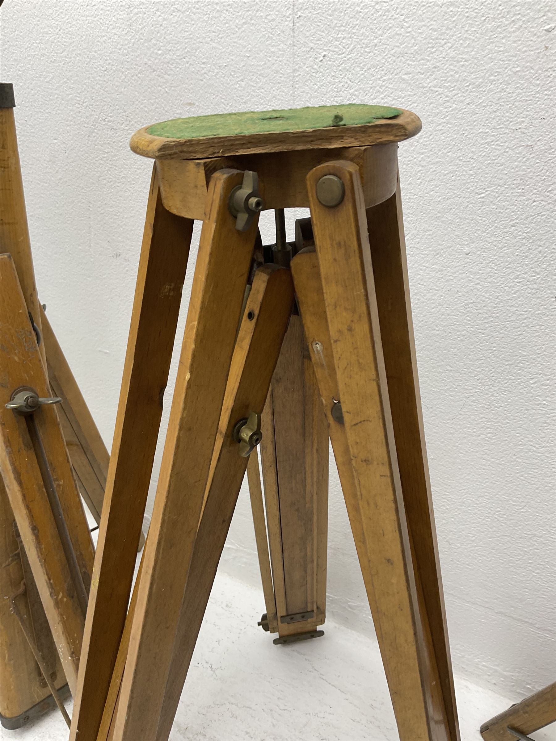 Three wooden adjustable tripods for plate cameras, together with a Linhof of Munchen metal tripod in a canvas case 
