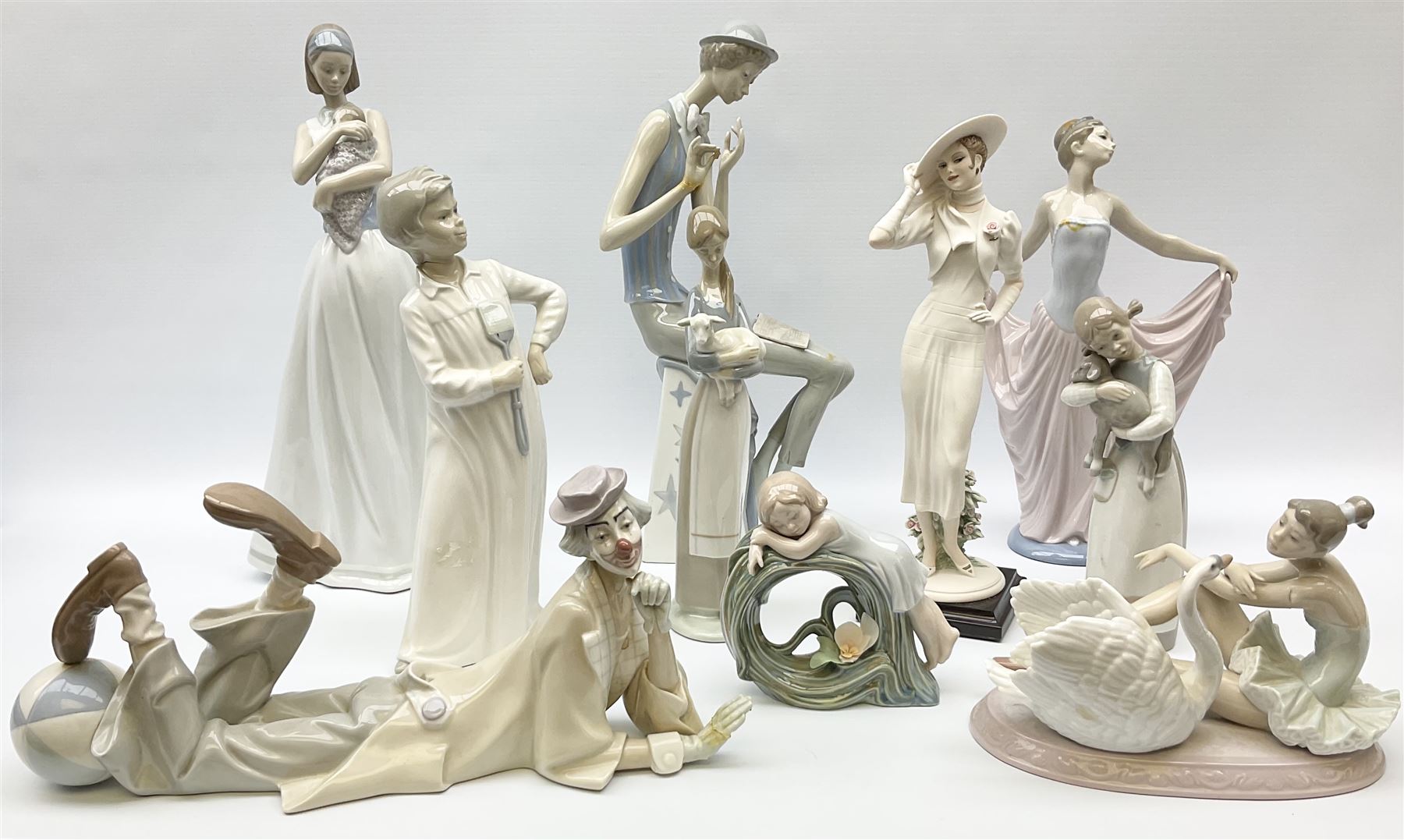 Collection of seven Lladro figures, including Seated ballerina with swan 6204, Childhood Dream 8129, Dancer 5050, reclining clown with ball alongside a selection of other figures. 