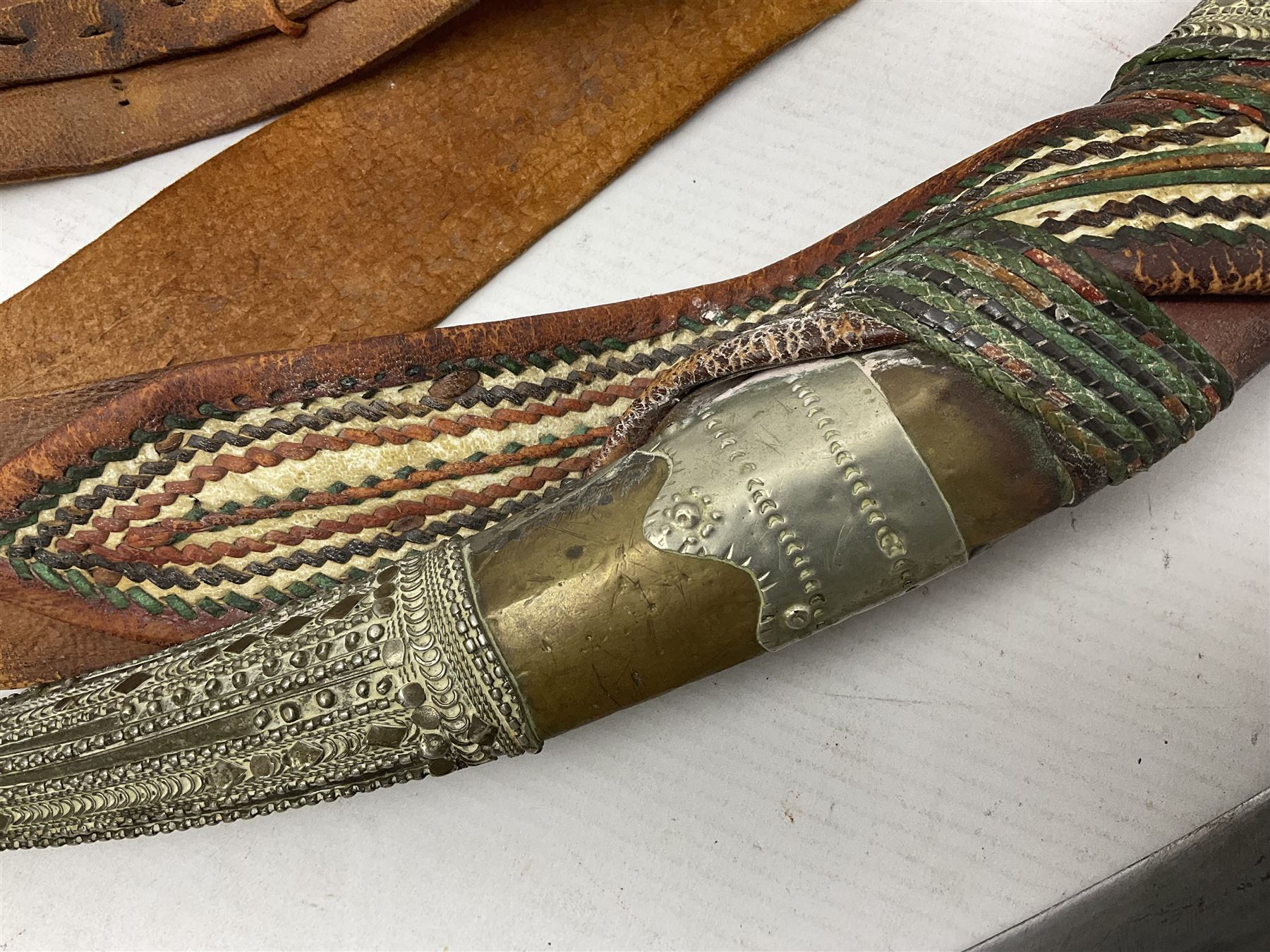 Saudi Arabian khanjar dagger with 29.5cm curving double edged  steel blade; white metal and copper mounted horn grip; in white metal mounted brass and leather scabbard incorporating embroidered leather wearing strap