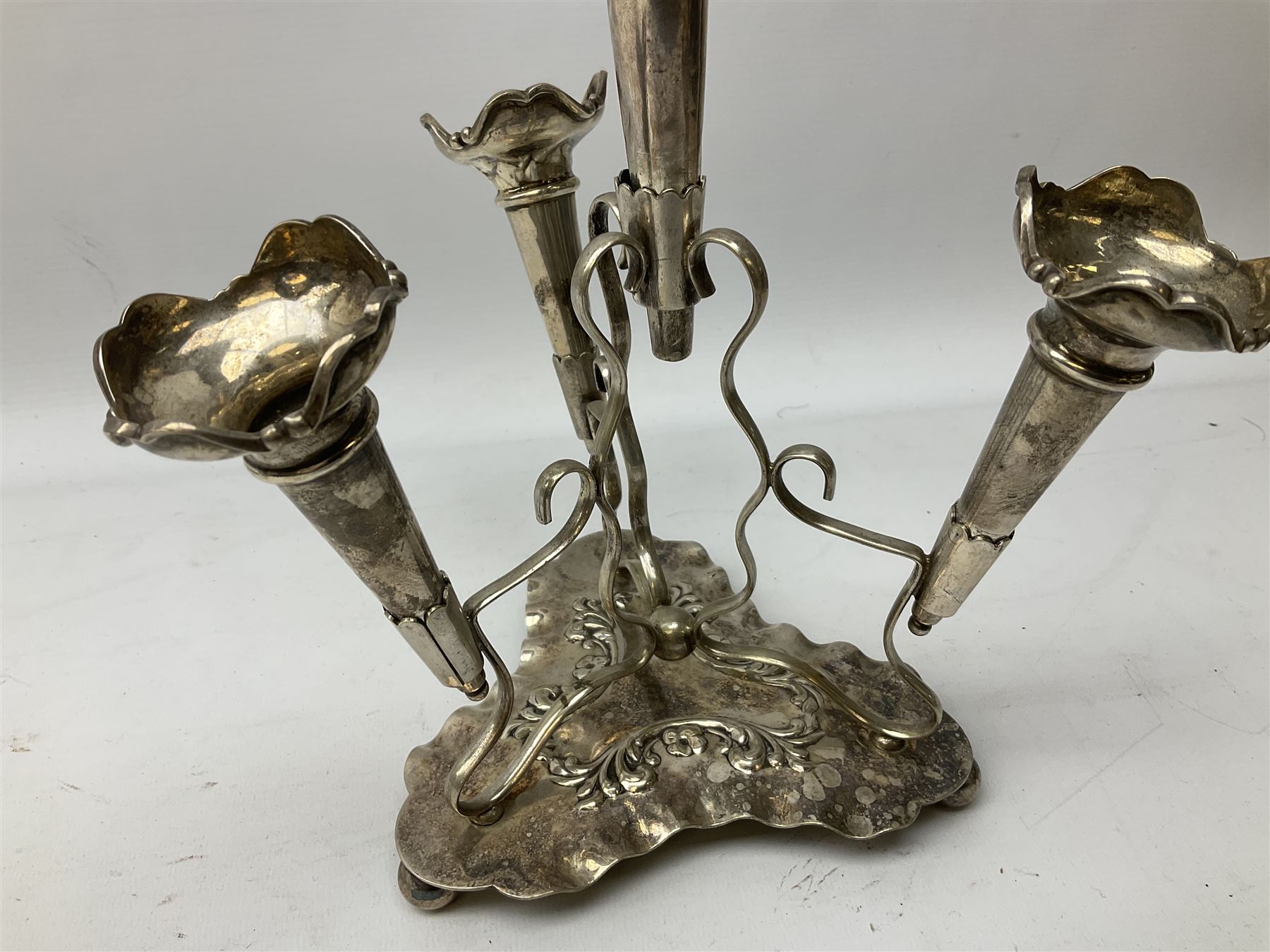 Four hallmarked silver trumpet vases, total weight 108g, upon silver plated stand with foliate decoration and bun feet