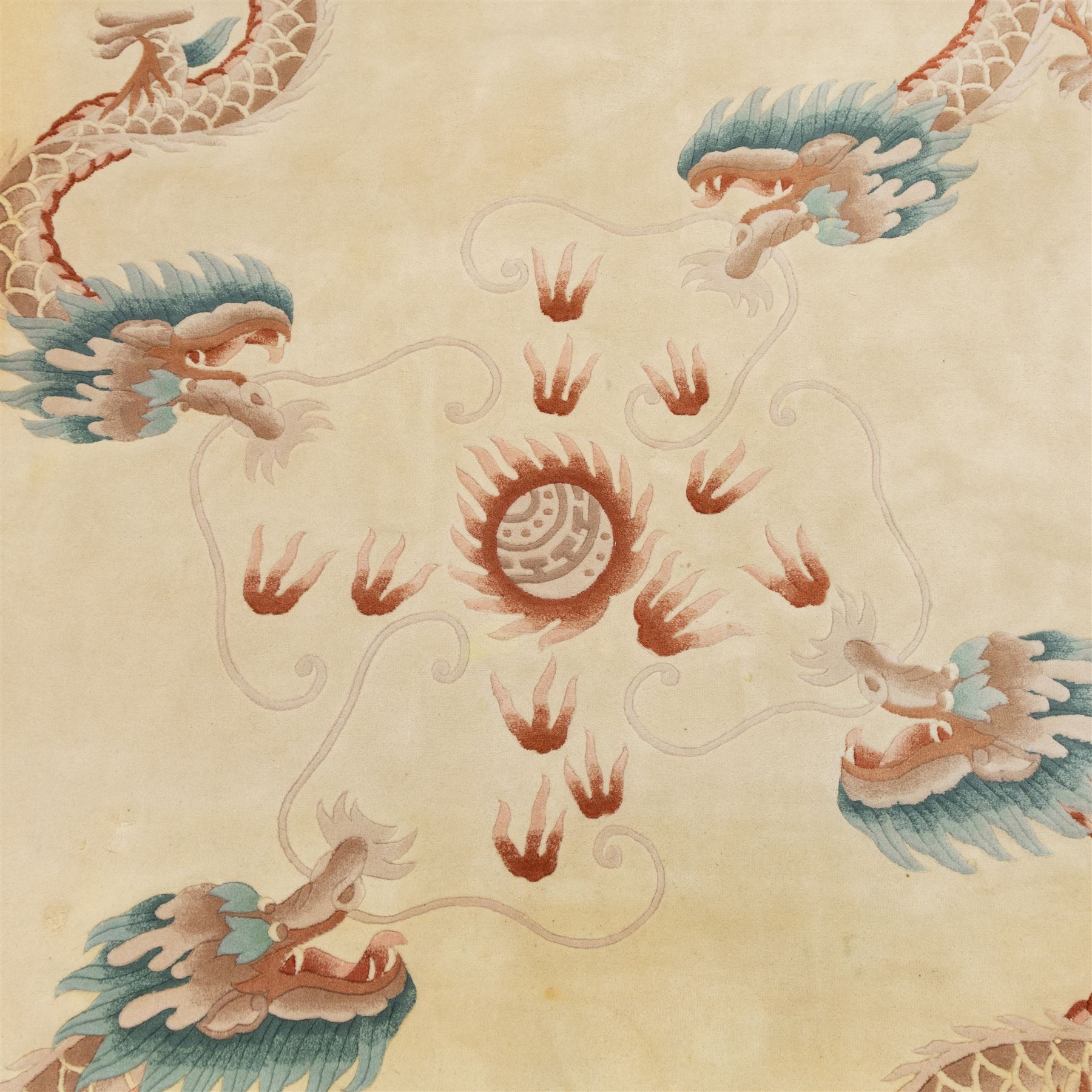 Late 20th century Chinese wool carpet, cream field with five stylized dragons arranged in a circular formation around a central flaming pearl motif, dragons depicted with elongated bodies and clawed feet amongst stylized cloud forms, enclosed within a narrow inner border and a wider outer border decorated with traditional Chinese motifs and symbols