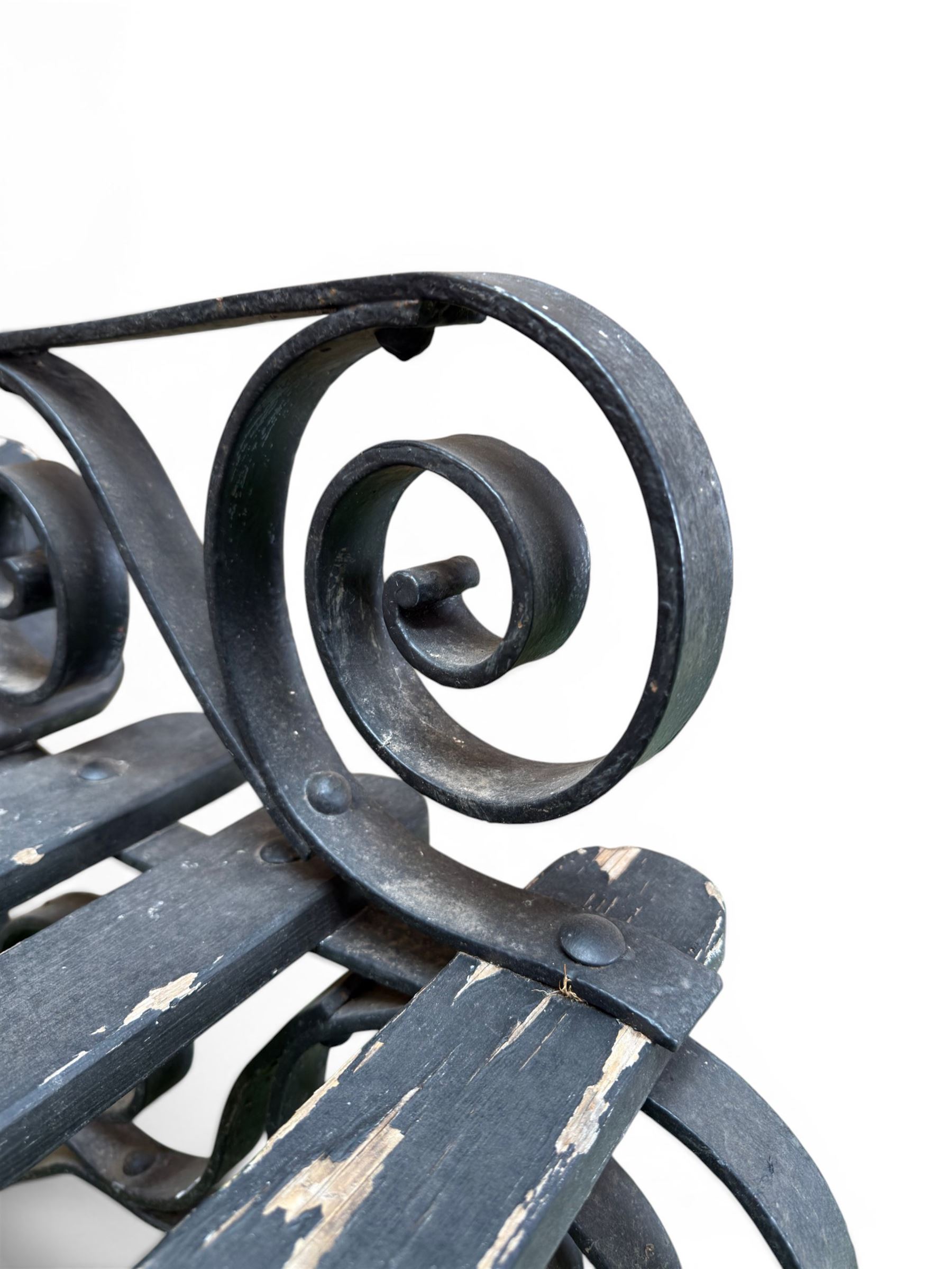 Coalbrookdale - rare pair of wrought iron and slatted wood garden benches, the twin wrought iron strapwork bench-ends formed of four scrolls over splayed feet, number 77 in the Coalbrookdale Castings Catalogue (see illustration)