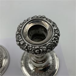 Four George III silver candlesticks, each upon knopped stem and weighted circular stepped foot, the foot and removable sconce repousse decorated with a band of flower heads, hallmarked to sconce and foot Thomas & John Settle, Sheffield 1820, H17.5cm