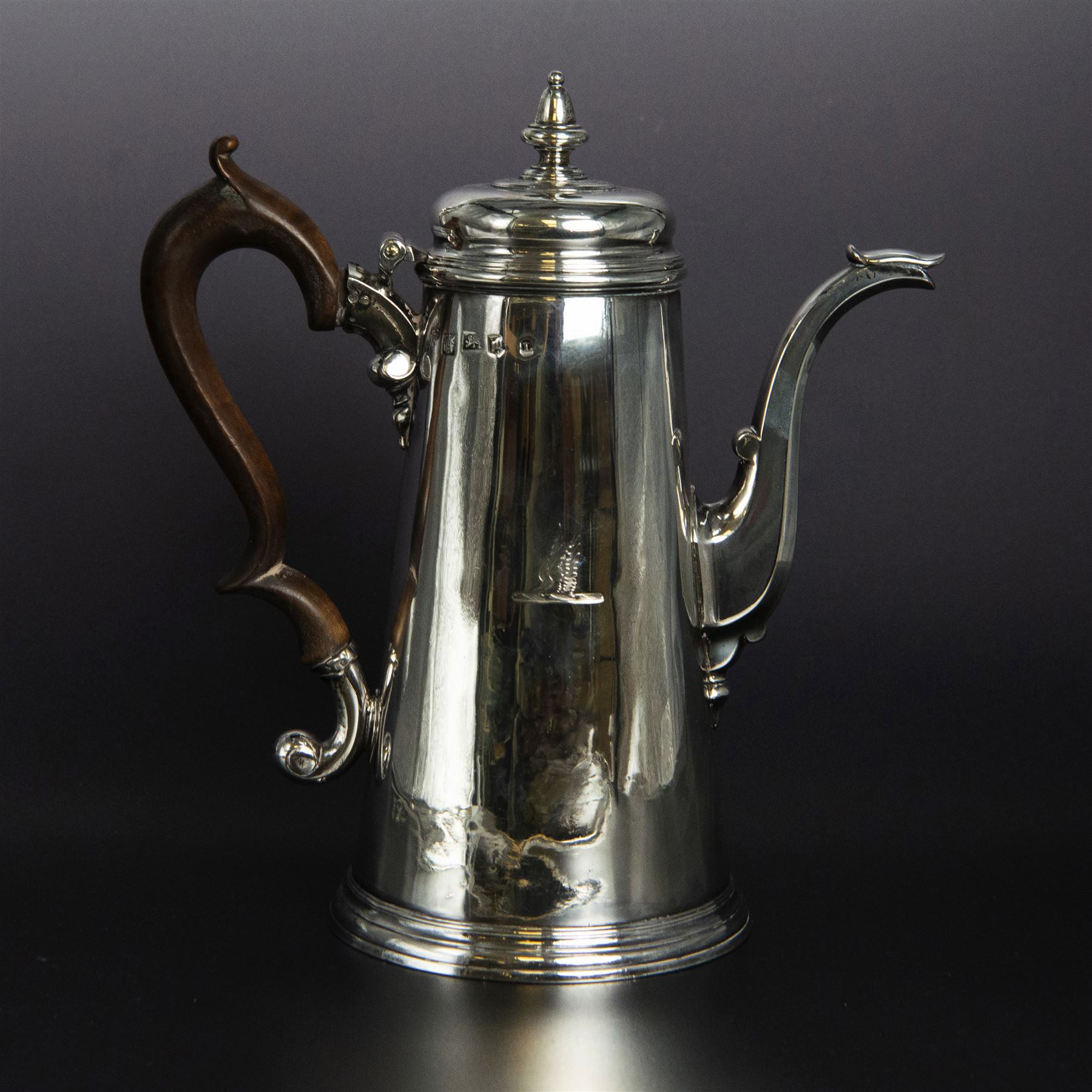 George II provincial silver coffee pot, of tapering cylindrical form, with wooden scroll capped handle, hinged cover with bell finial, and engraved crest to body, hallmarked John Webber of Plymouth, Exeter 1759, H21cm