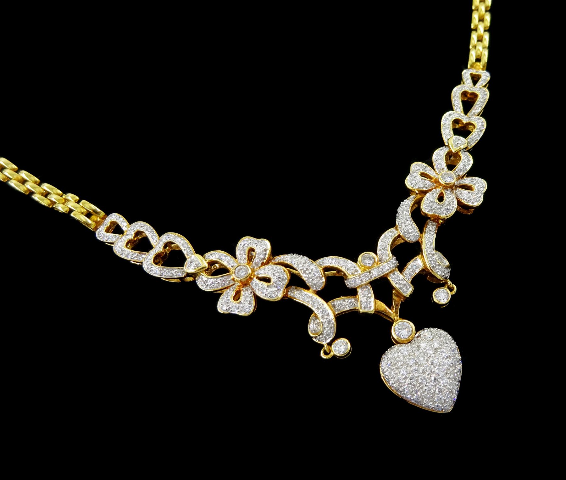 18ct gold diamond heart and bow necklace, the central panel set with round brilliant cut diamond hearts, bows and ribbons, suspending a further pave set diamond heart pendant, to a brink link chain necklace, stamped 750