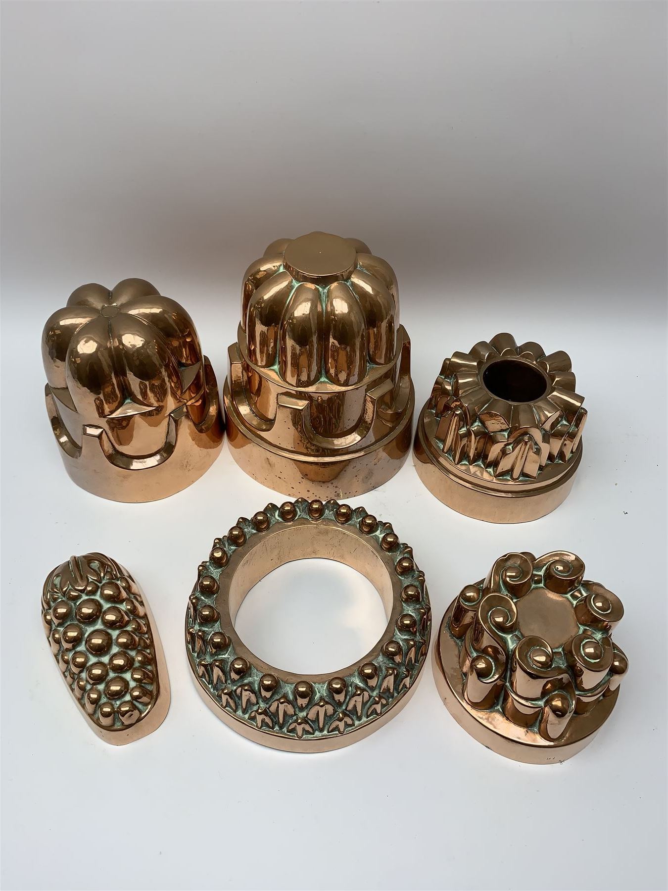 Six Victorian copper jelly moulds, five examples of castle type form, one example modelled as a bunch of grapes, largest H21cm