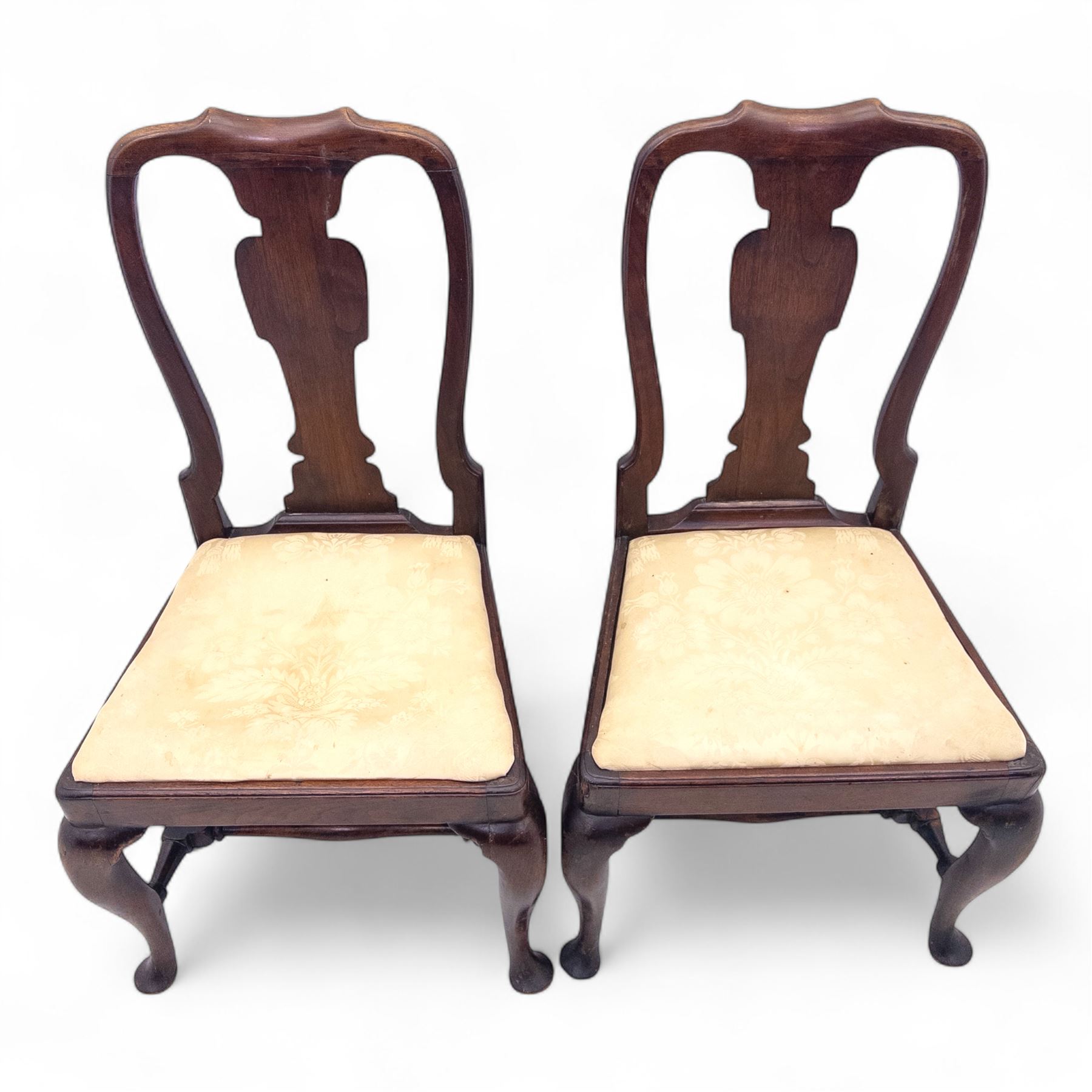 Pair of early 18th century walnut side chairs, vase-shaped splats beneath shaped top rails, drop-in seats upholstered in floral damask, on cabriole front legs terminating in pad feet, united by turned stretchers