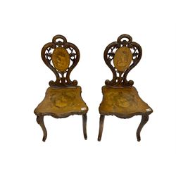 Pair 19th century Black Forest type inlaid hall chairs,  the shaped and pierced back carved with scales and flower heads, inlaid with hunting scenes, on cabriole supports