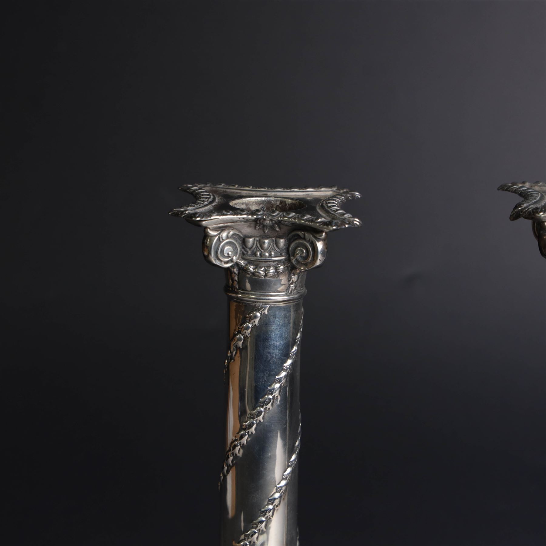 Pair of Edwardian silver mounted column candlesticks, each with embossed floral, foliate and scrolling decoration and upon stepped square weighted bases, hallmarked William Hutton & Sons Ltd, London 1901, H19cm