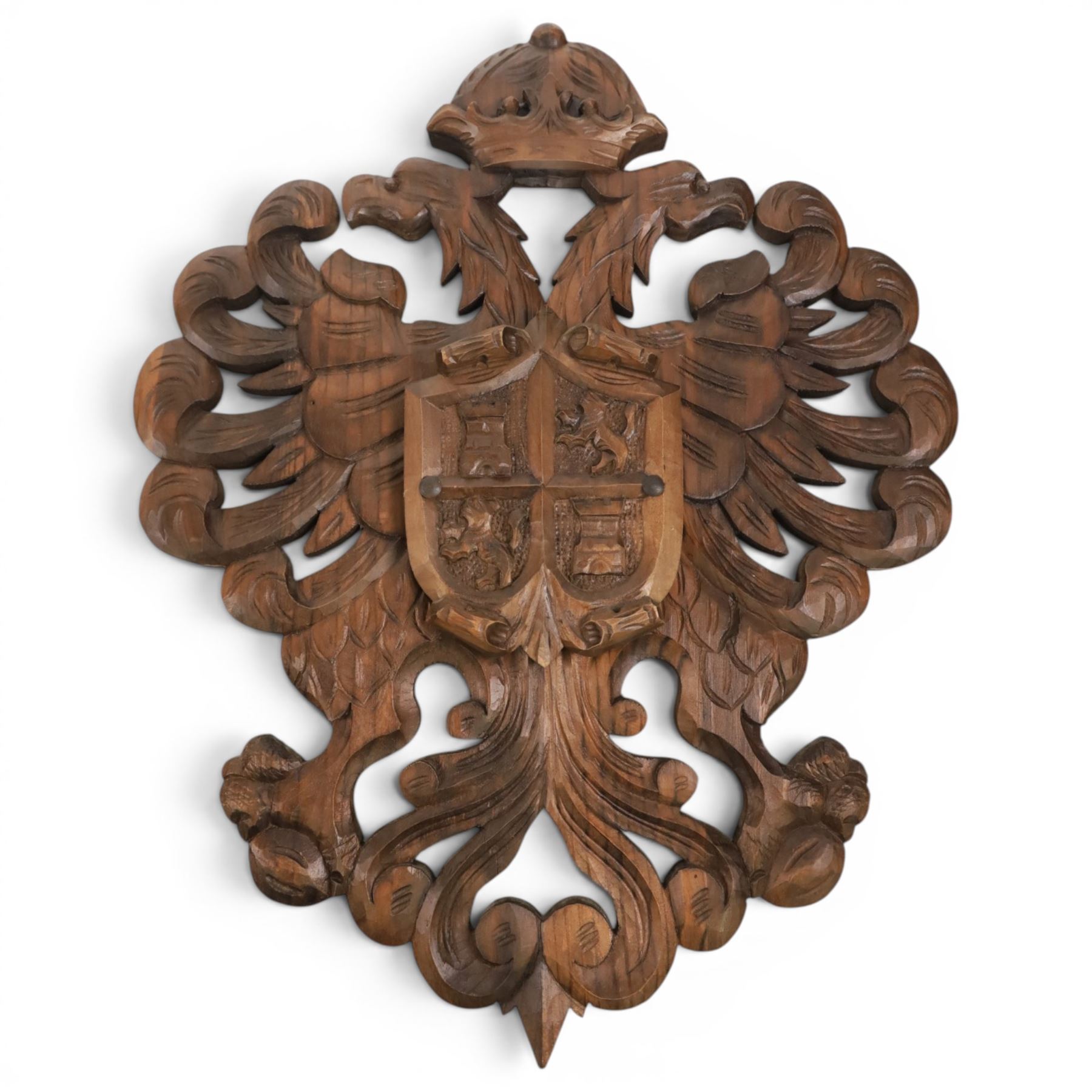 Carved wooden wall plaque, decorated with foliate scrolls, with two reproduction swords attached, together with five other wooden plaques with foliate scrolls and shields