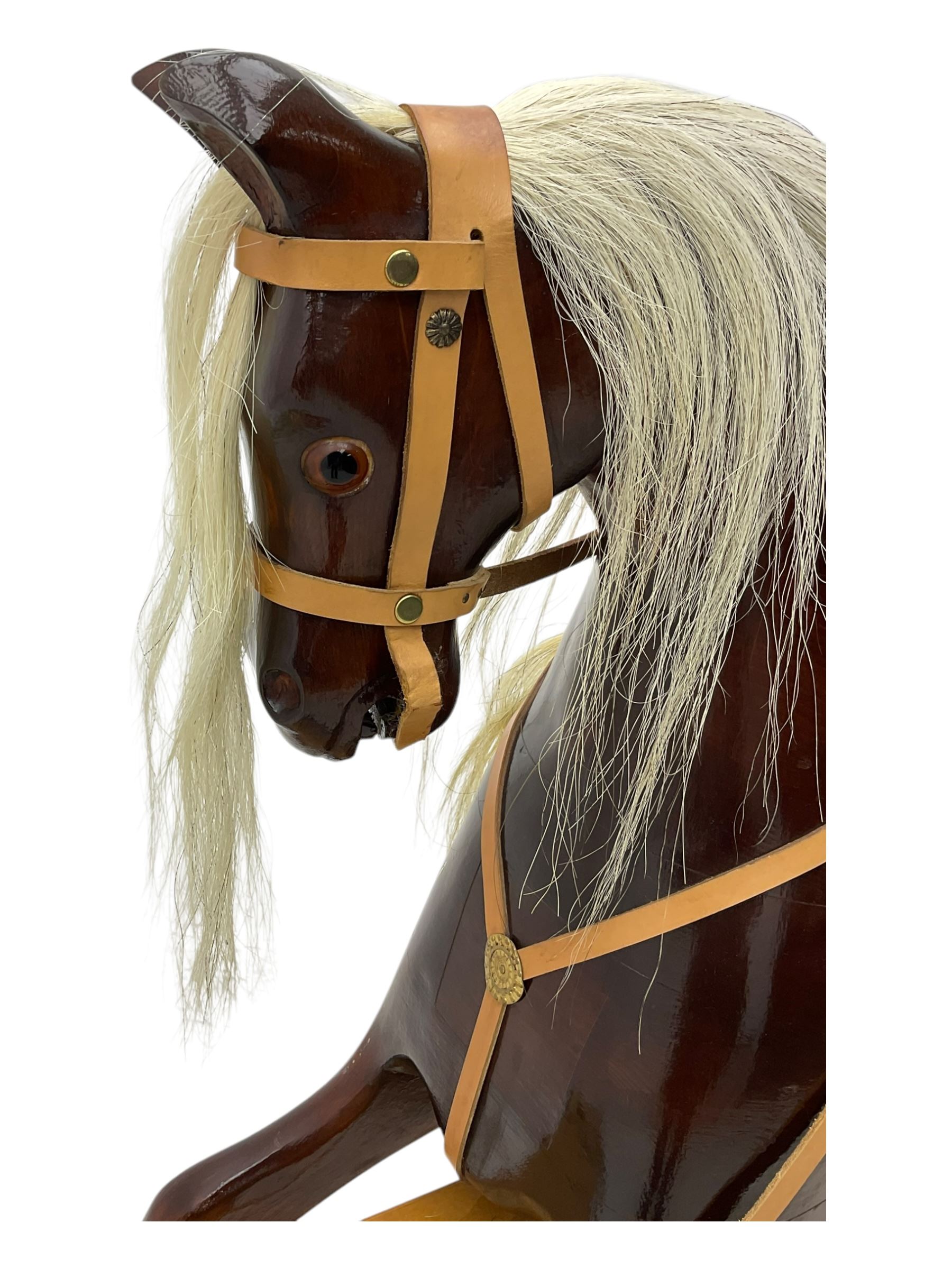 Contemporary carved wooden rocking horse, with leather saddle and bridle, horsehair mane and tail, raised on a pine stand with swing iron supports