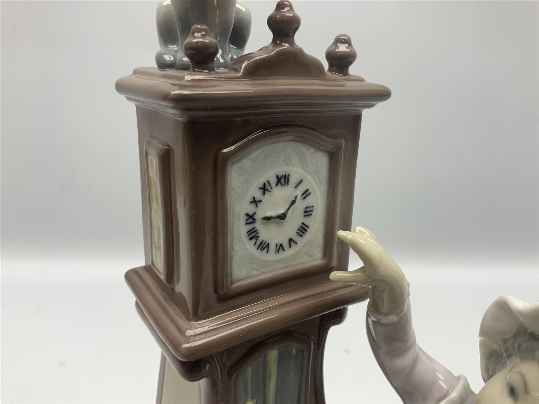 Lladro figure, Bedtime, modelled as a young girl reaching for her pet cat upon grandfather clock, sculpted by Vincente Martinez, with original box, no 5347, year issued 1986, year retired 1998, H28cm