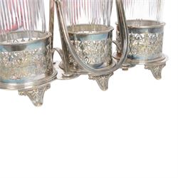 Late 19th century silver plated Silber & Fleming triple decanter stand, the three cut glass decanters with spire stoppers housed within foliate and scroll pierced bottle sleeves, upon a tripart base with six scroll feet, the base mounted with articulated x-frame curved handle, including handle when positioned upright H35.5cm, W34cm