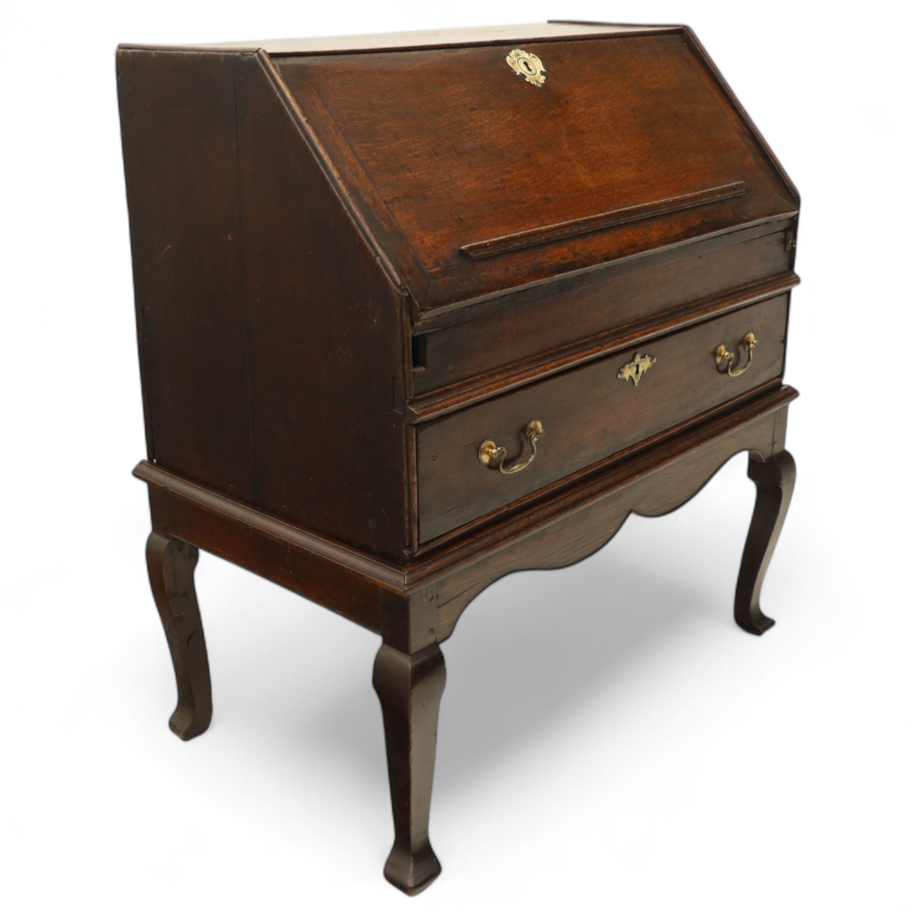 Early 18th century George I oak bureau on original stand, the fall front enclosing an arrangement of correspondence drawers and pigeonholes over central well, fitted with single long drawer below, the shaped apron over cabriole supports with pad feet