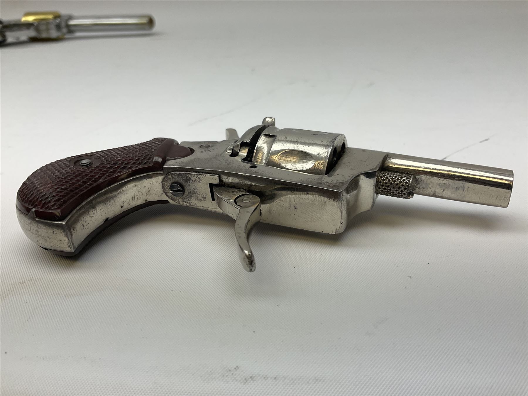 Early 20th century Flobert 5mm blank firing revolver with six-shot chamber, top venting, nickel plated with folding trigger No.118 L12.5cm overall; replica non-firing 'British Bulldog' revolver; and Windproof gas lighter inscribed 'Revolver-99 Spring and Autumn' in holster marked 'Star-Line'