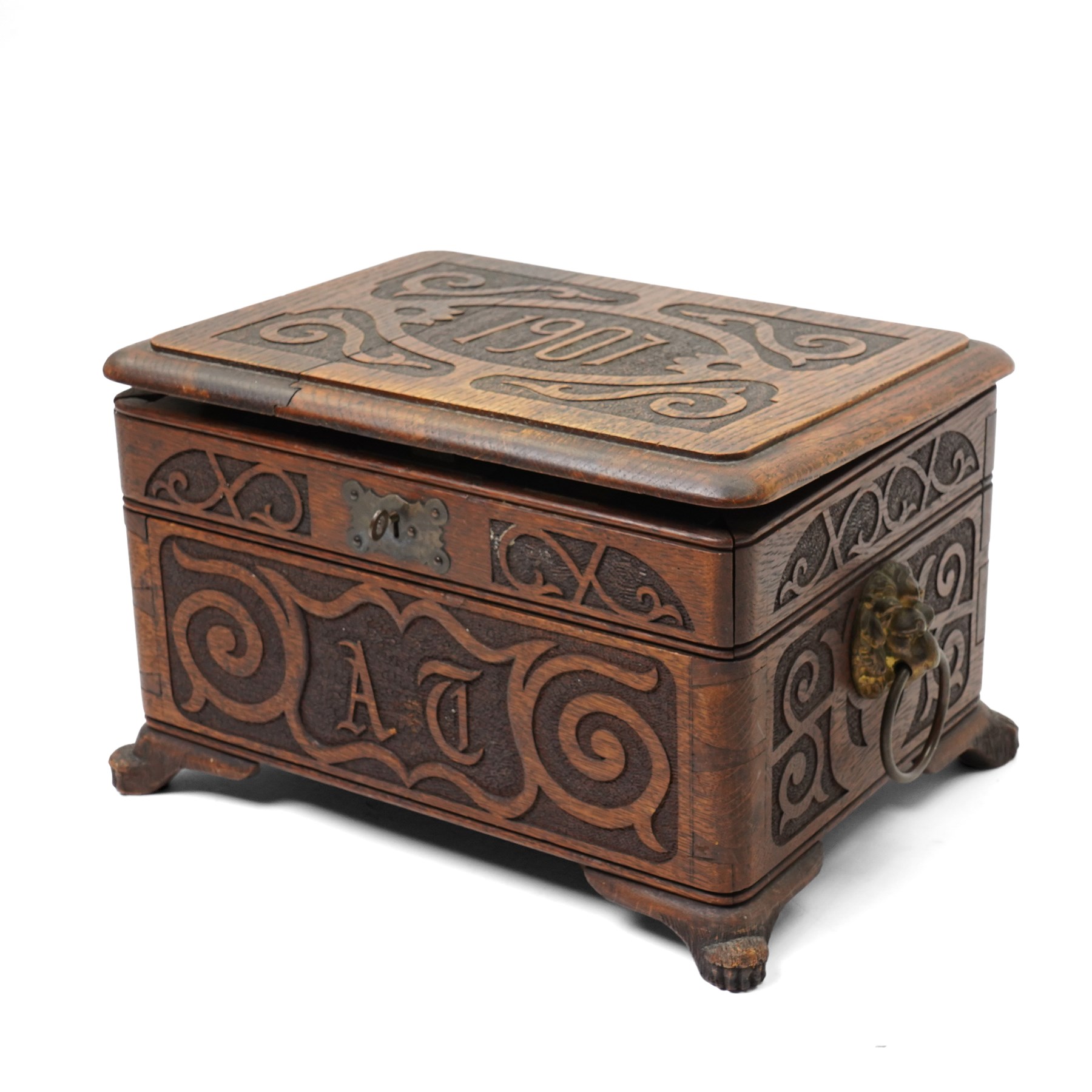Arts & Crafts Design oak sewing box carved with initials and dated 1907, with sliding top, lion mask ring handles on shaped supports. W36cm