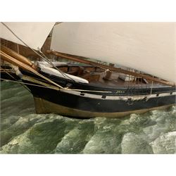 Large early 20th century diorama with three waterline sailing vessels at sea, two named 'Annie' and 'John', with painted background of a rocky coastal scene, in hardwood display case with glazed front and sides and rope twist beading W119cm H61cm D49cm