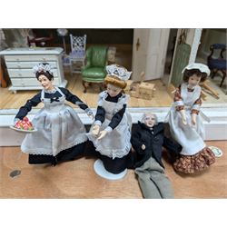 Two modern three storey dolls houses, each painted green with decorated interiors, both upon a single white wooden base, together with a large collection of dolls house furniture, accessories and figures 