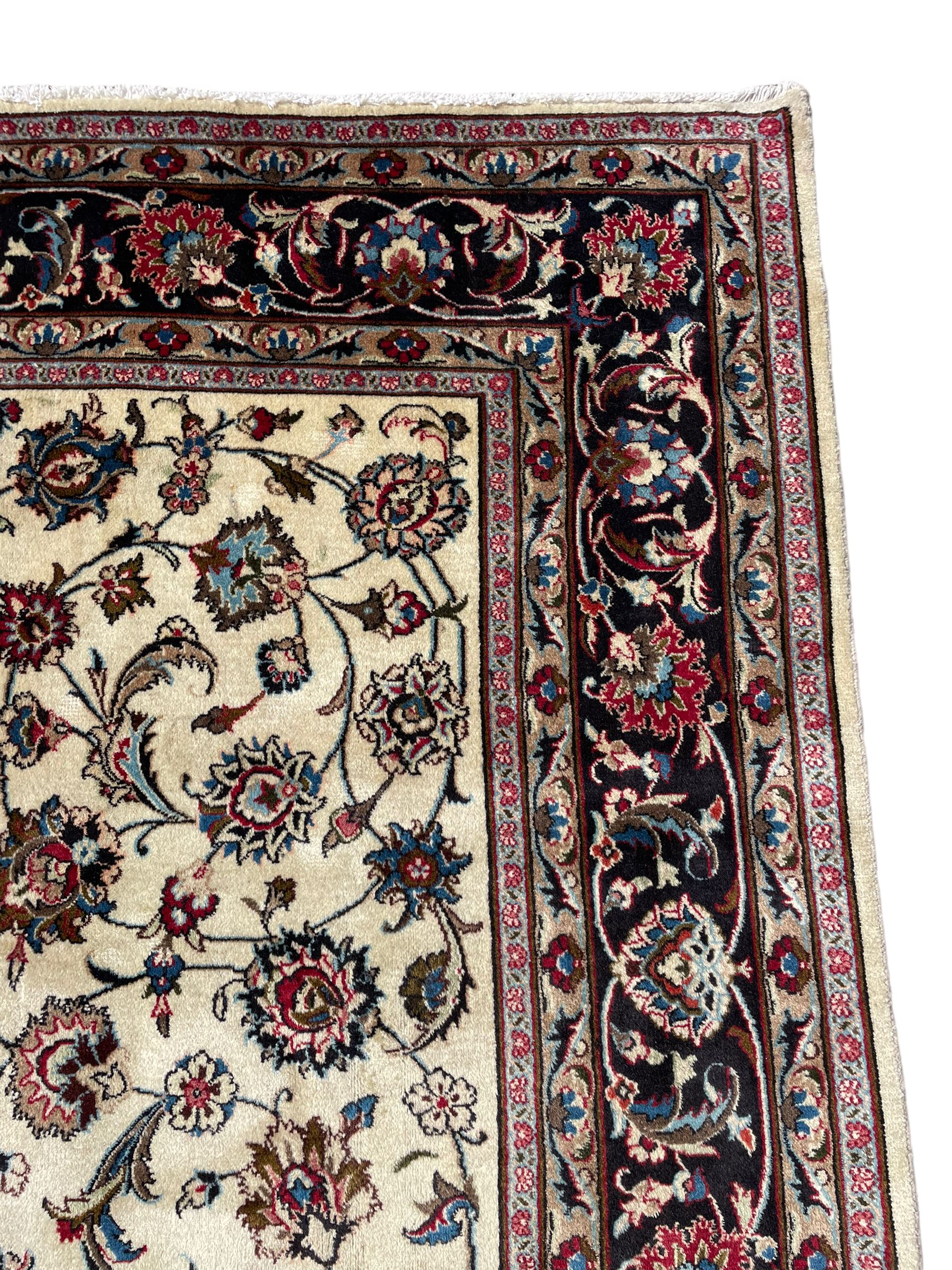Persian ivory ground rug, the field decorated with interlaced and scrolling foliate with palmettes, the dark indigo border with stylised plant motifs surrounded by scrolled branches