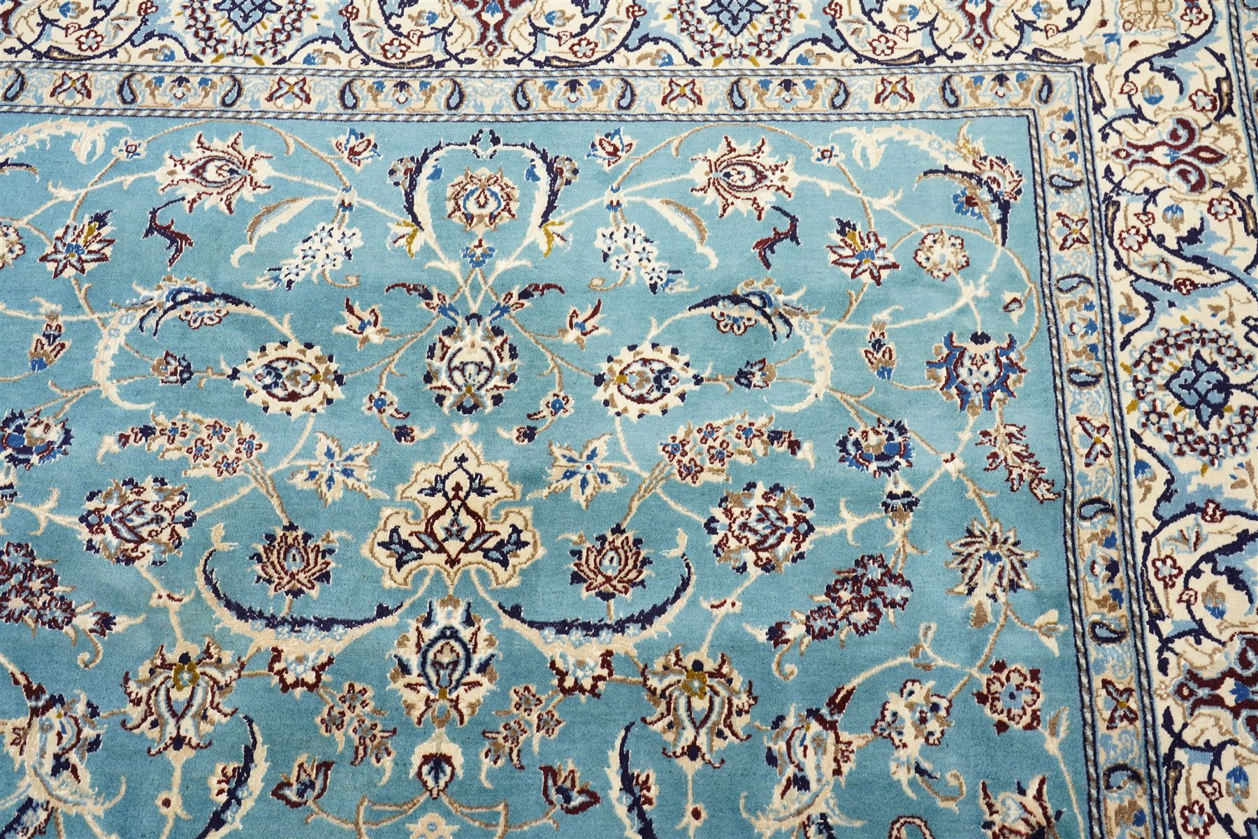 Central Persian Nain hand-knotted carpet, soft sky blue ground with central cusped medallion of radiating palmette form, issuing scrolling vine work, arabesques, and delicate floral sprays, spandrels of conforming design, main border of ivory ground decorated with scrolling vine work palmettes and stylized floral motifs, flanked by narrow guard stripes, with cotton fringe ends 