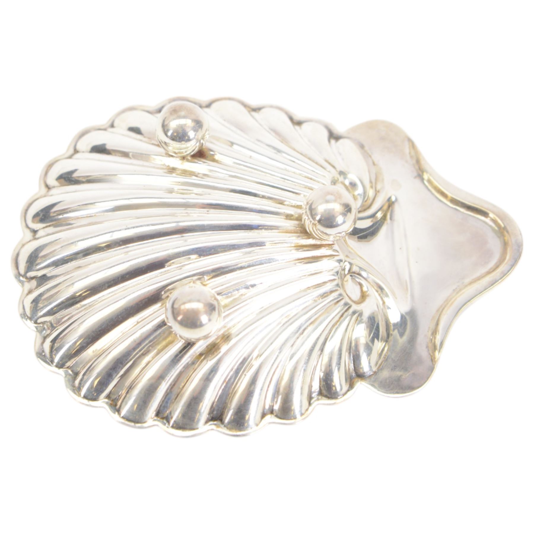 Edwardian silver shell butter dish, upon three bun feet, together with a matching shell spoon engraved with initial, both hallmarked Josiah Williams & Co, London 1906 and 1914, together with an Edwardian milk jug, open sucrier and sugar tongs, the jug and bowl of circular part fluted form with bead rim, hallmarked Mappin & Webb Ltd, Sheffield 1902, both sets contained within fitted tooled leather boxes with silk and velvet lined interiors