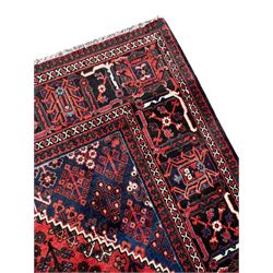 Persian Joshaghan crimson ground rug, stepped lozenge medallion surrounded by repeating foliate lozenge motifs, the border decorated with stylised plant motifs, within geometric guard stripes